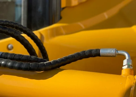 Hydraulic hose with a steel fitting on yellow machinery